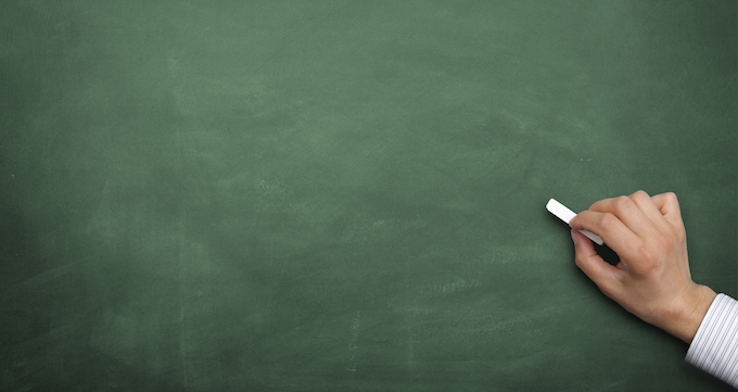 AERO: Hand with chalk about to write on an empty blackboard